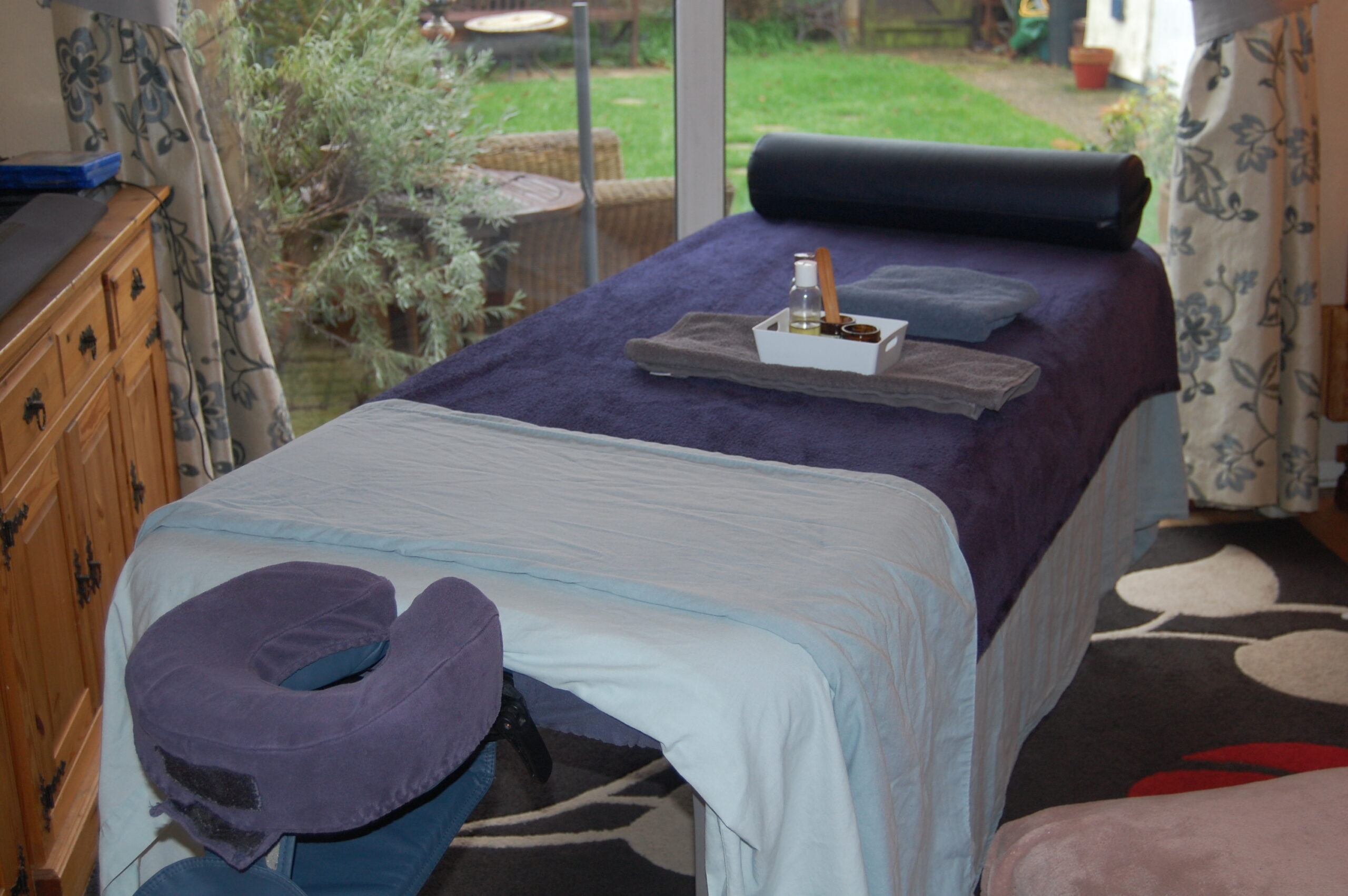 a massage couch covered in a blue sheet with dark blue fleece set up in a living room