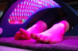 pair of feet of a person lying down with the celluma light therapy unit over them